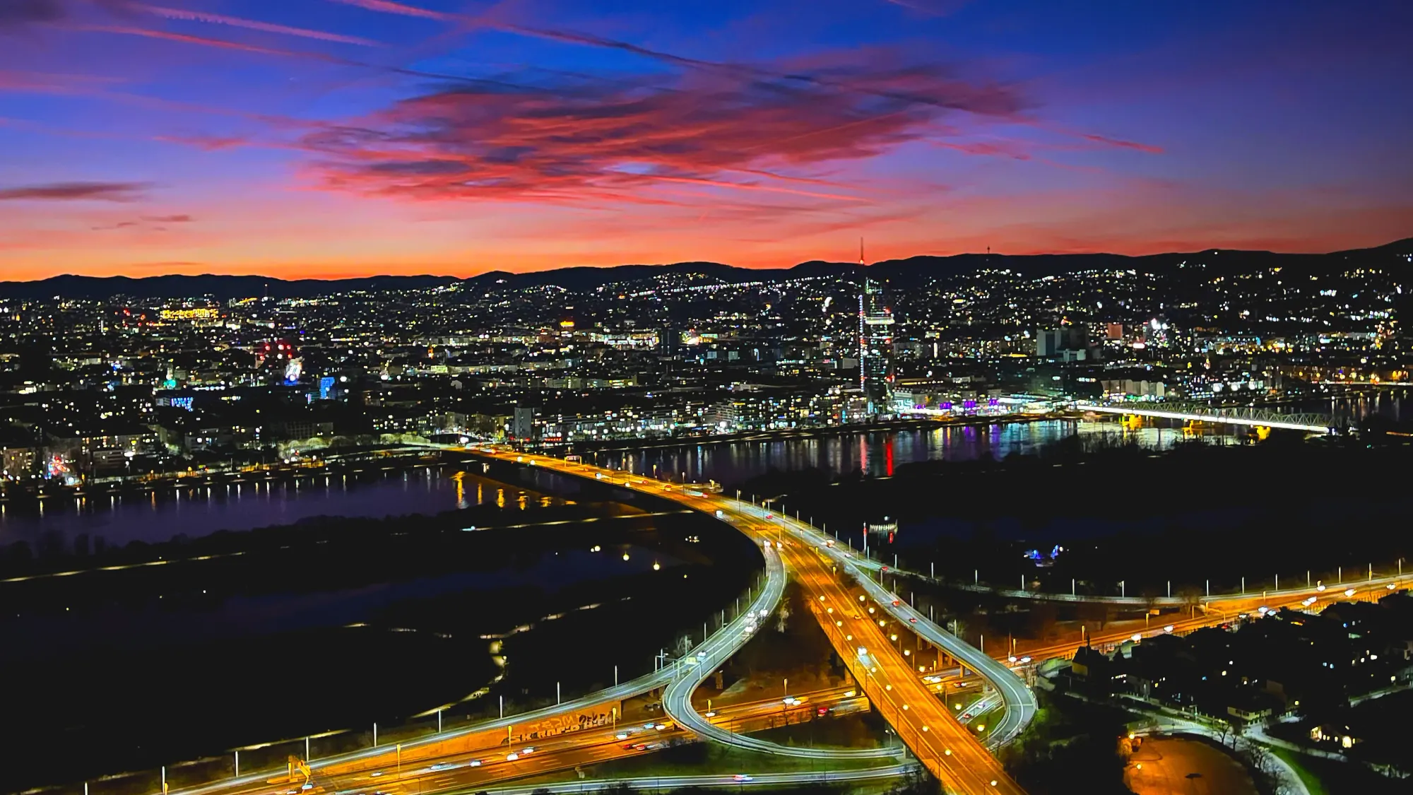 The city lights just after dusk when the sky has bright colors but the buildings are dark