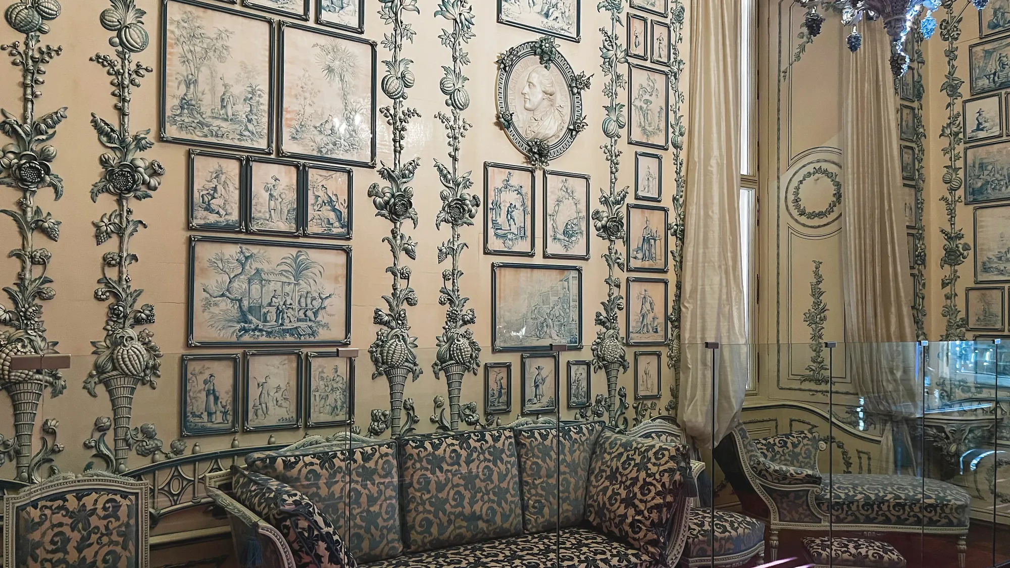 A cream colored room with blue paintings and blue floral couch