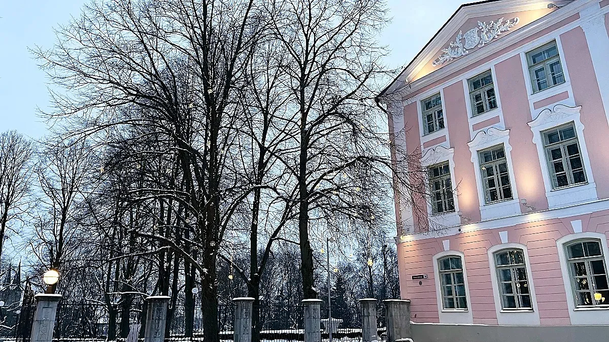 Pink building with white trimming next to a wintry garden