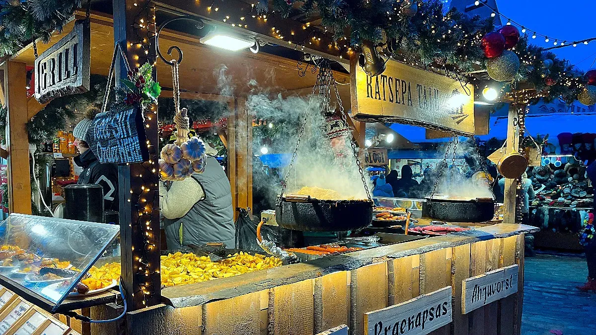 Wooden stall with hanging cauldrons of food and wreaths with lights for decor