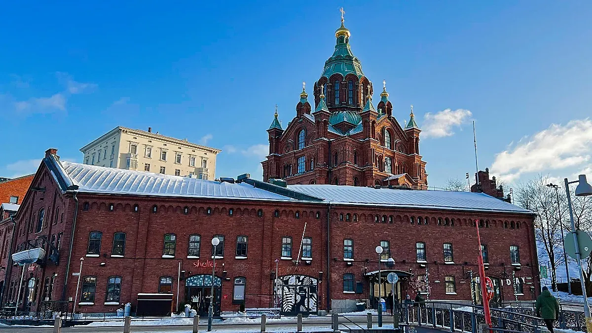 Snow covered brick building resting in front of a brick and copper church steeple