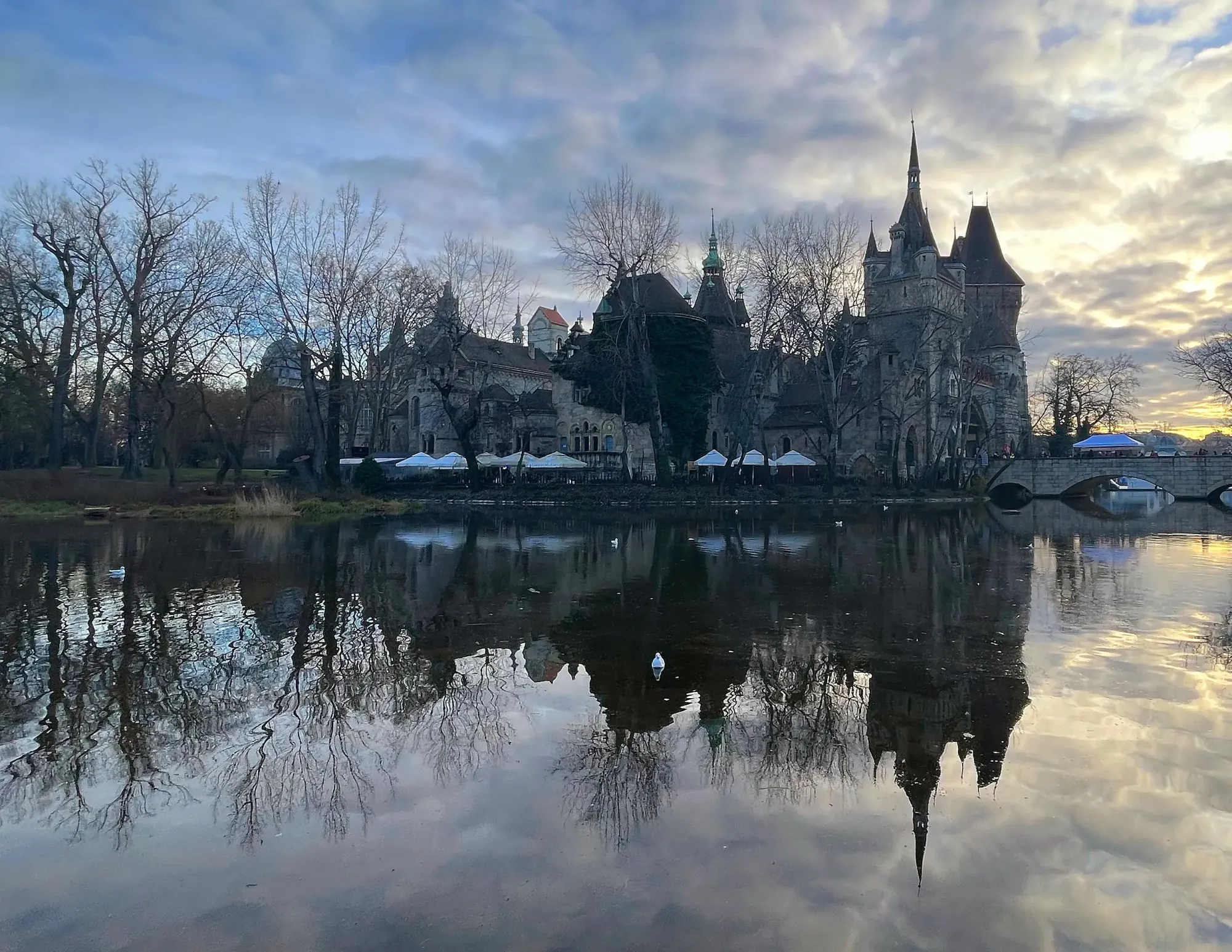 Grey stone castle and dusky clouds reflected in a mirror-like lake