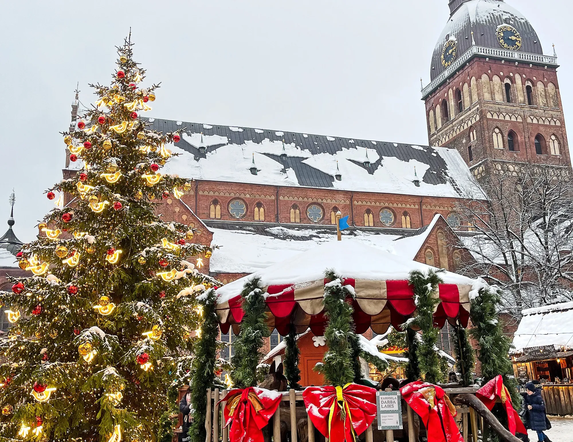 Tinsel tree and bedecked gazeebo in front of a brick church covered in snow