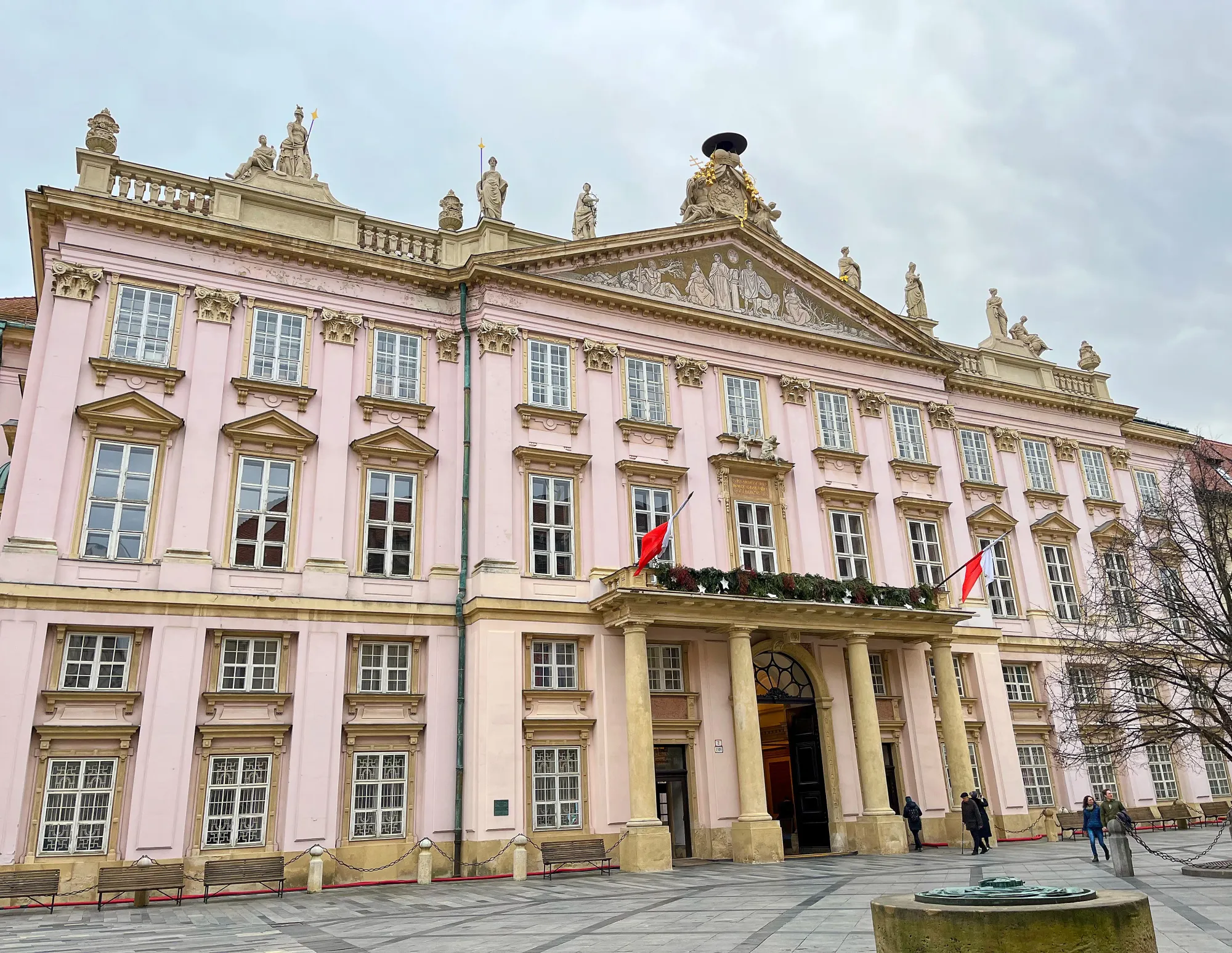 Ornate pink building with tan stone columns and statues