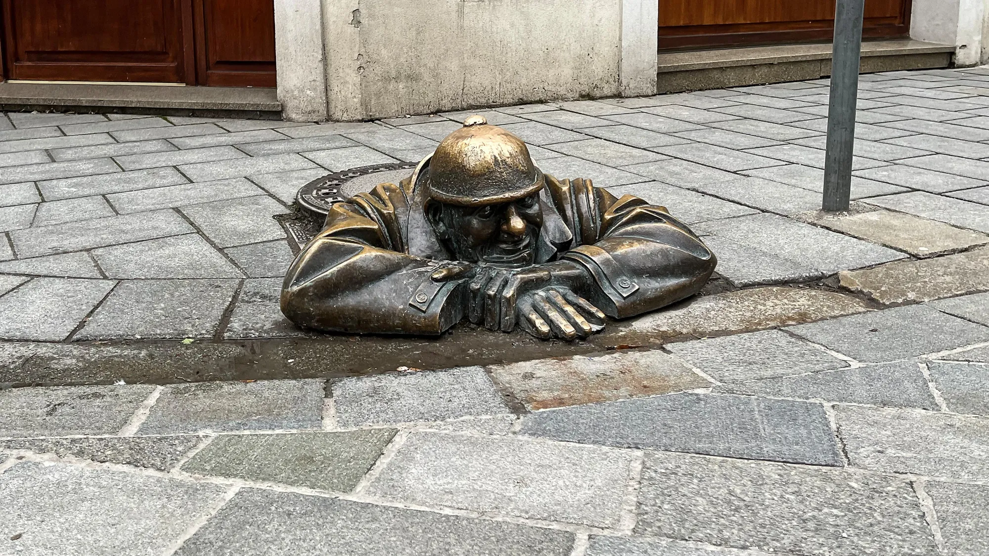 Bronze sewer worker statue popping its head out of a manhole