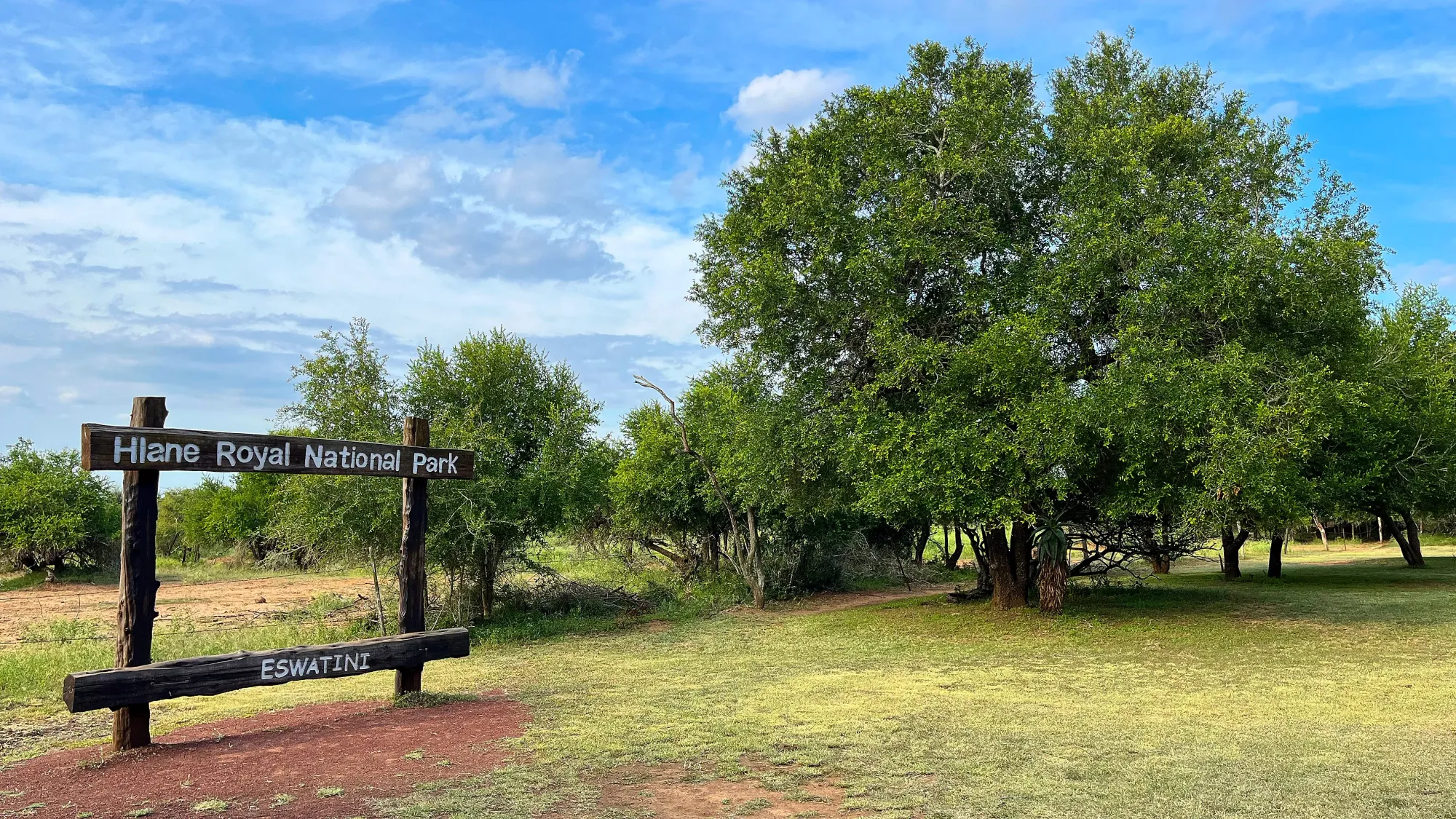 Wooden frame naming the park in front of grass and a large tree