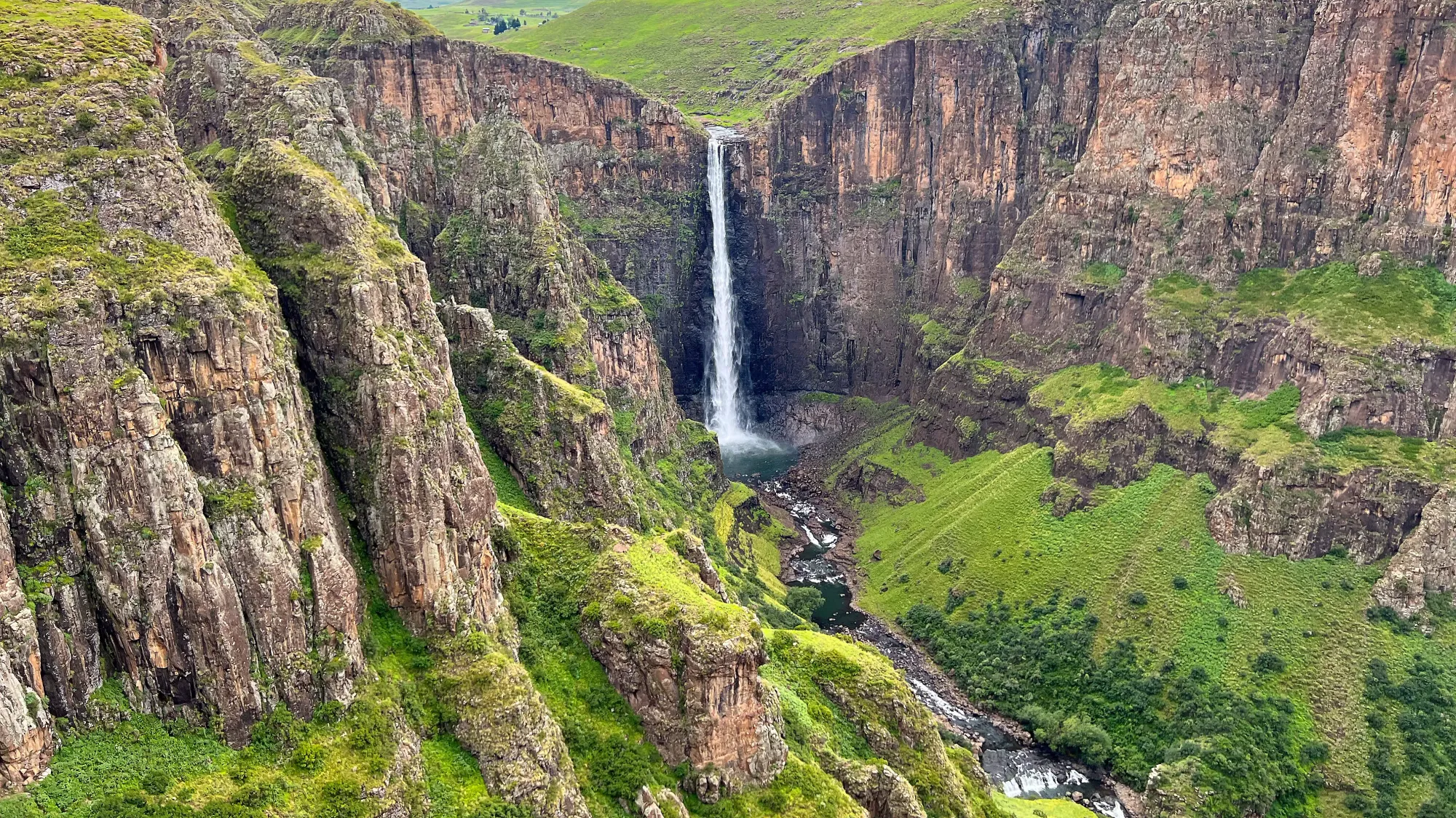 Grass covered rock face with a waterfall in the middle