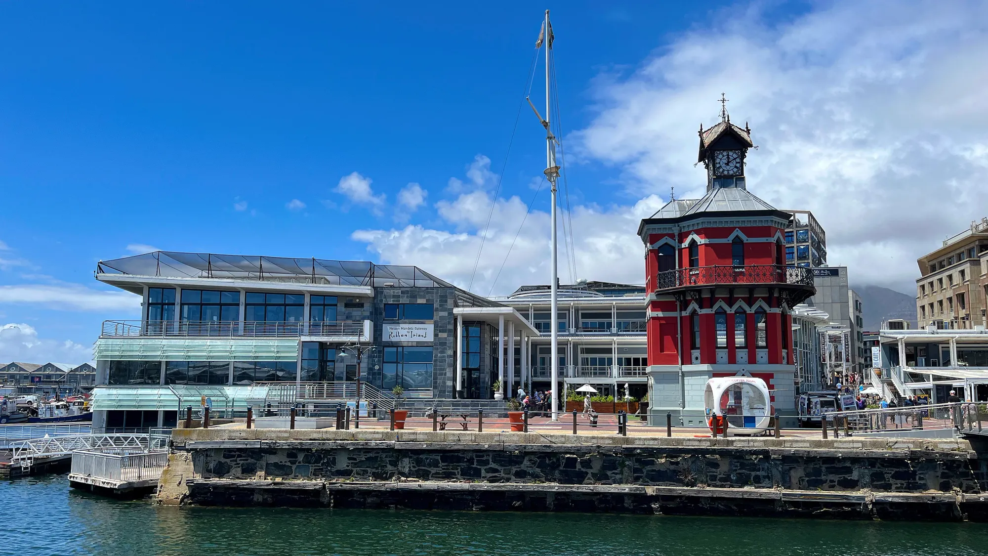 Glass buildings with a red tower on the water