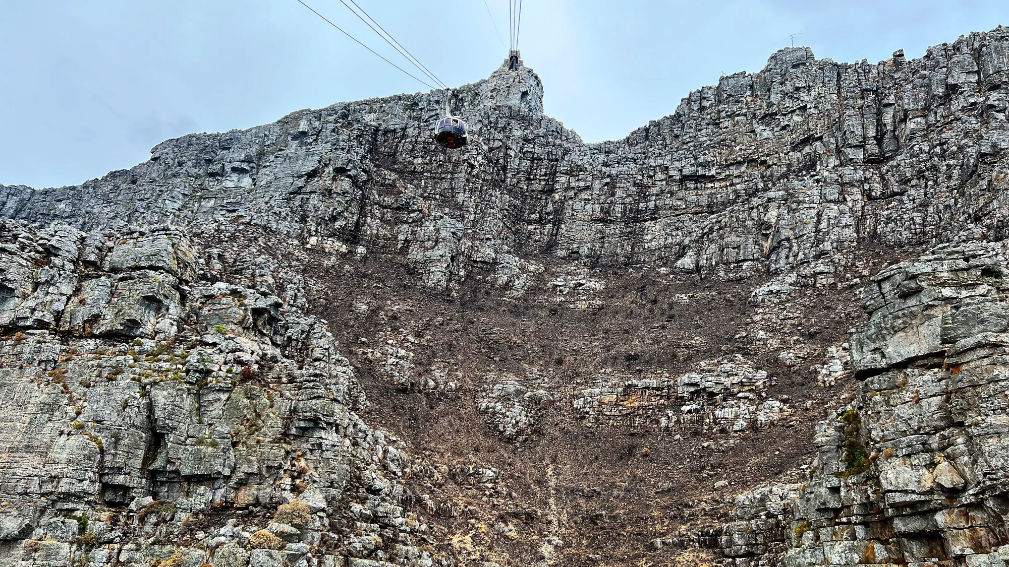 Rock face with a round cable car and accompanying wires draping from it