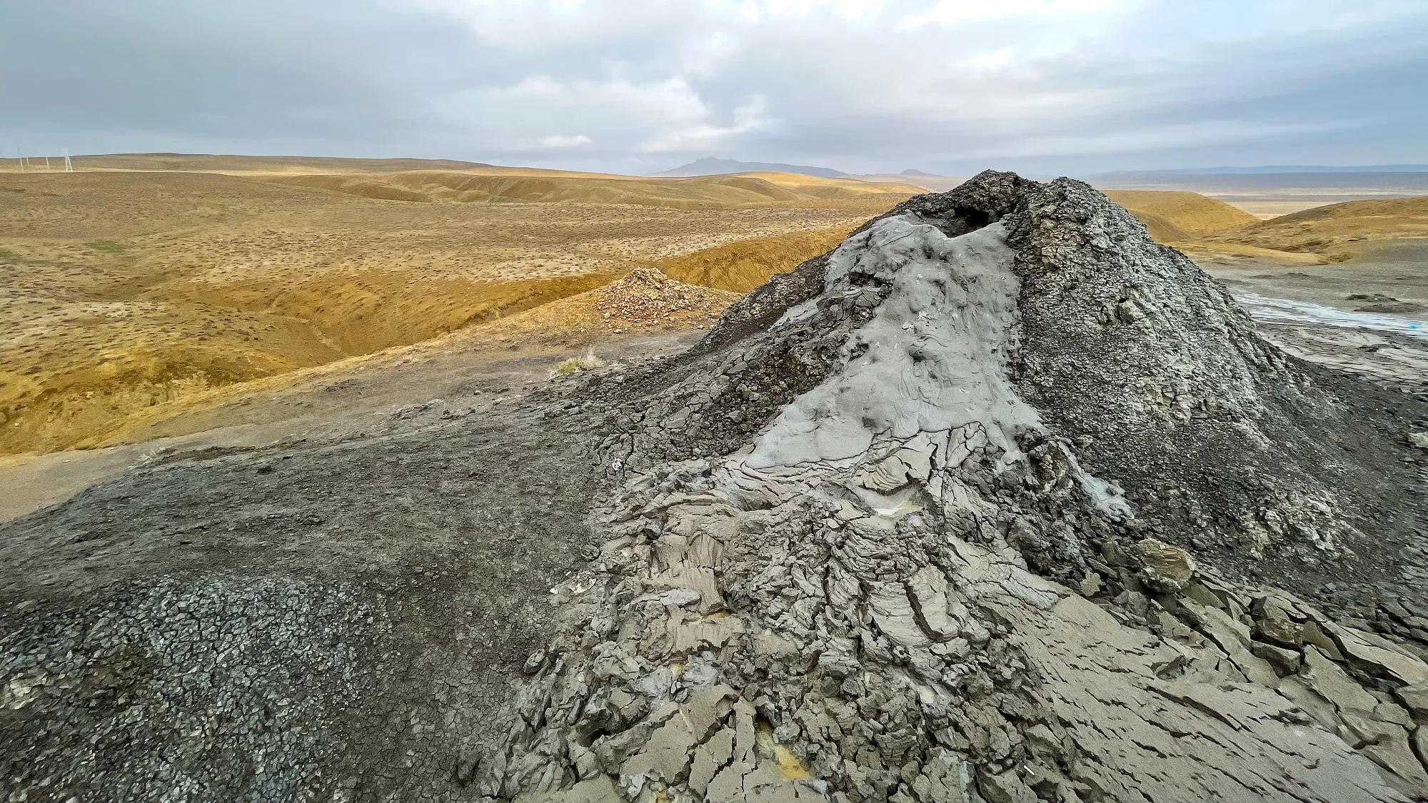 Grey mound of coagulated grey mud billowing out of the top of the volcano