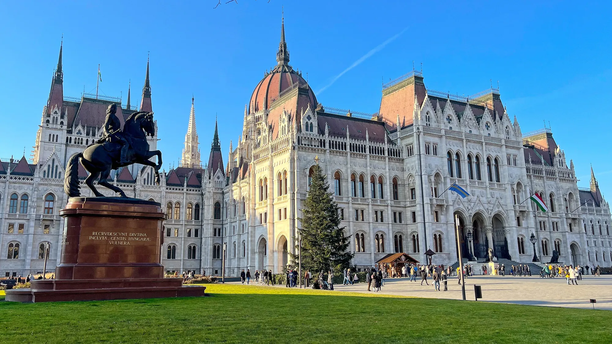 White ornate building with a mounted horse statue in on the lawn in front of it