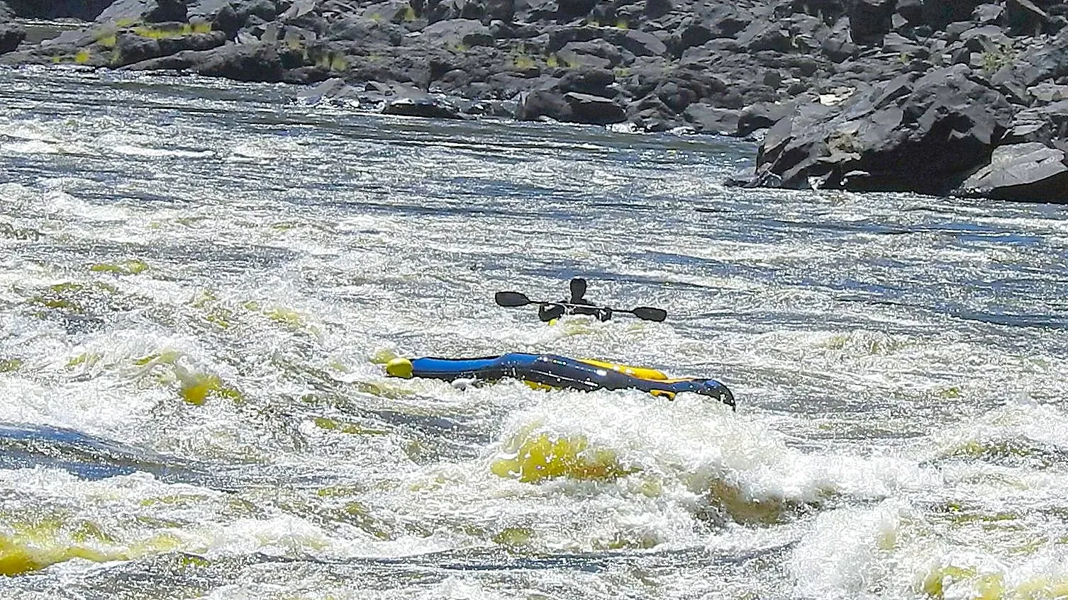 White water rapids with a capsized raft flipped upside down