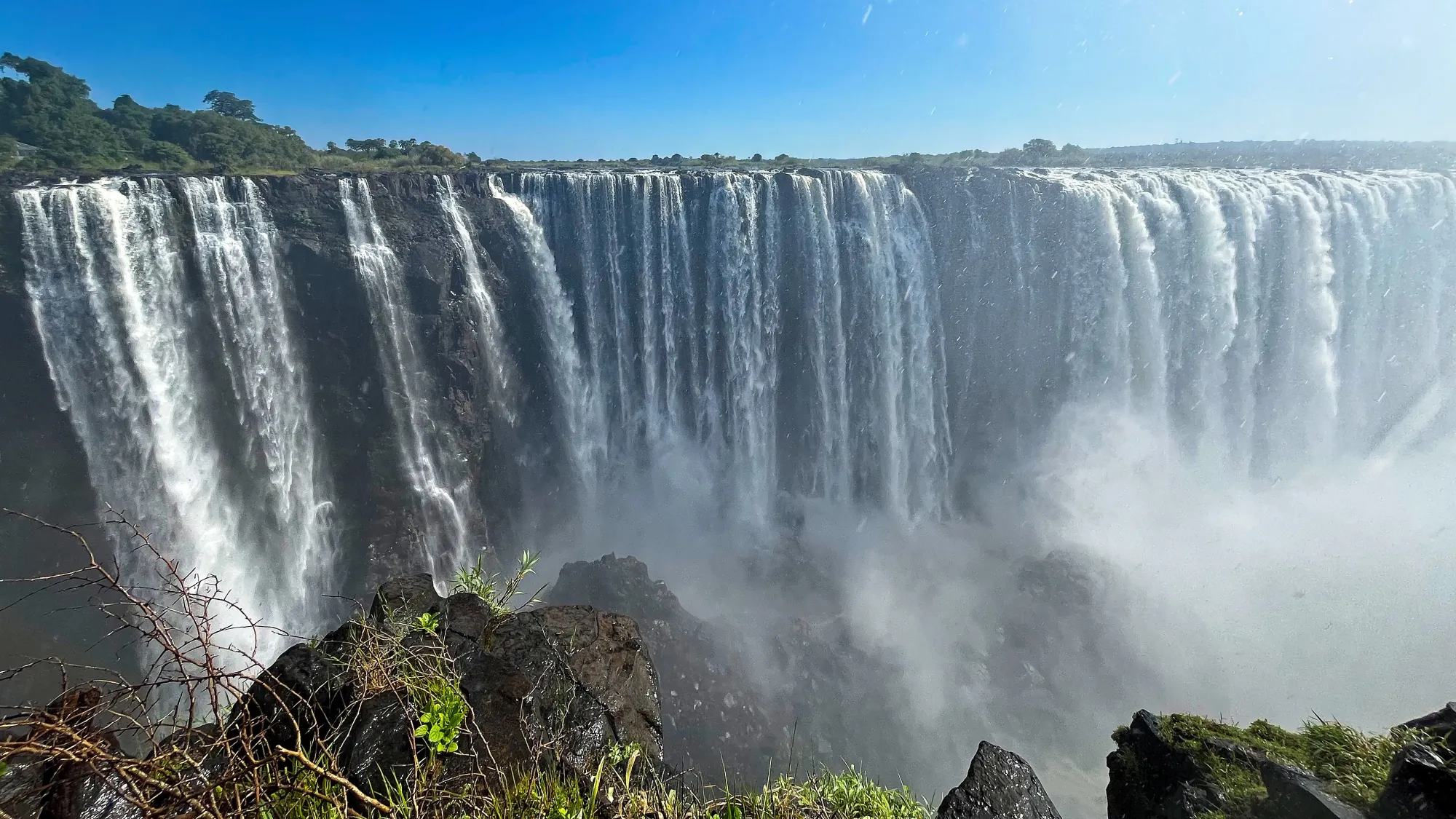 Wide angle of water pouring off the side of the rocks into the misty abyss