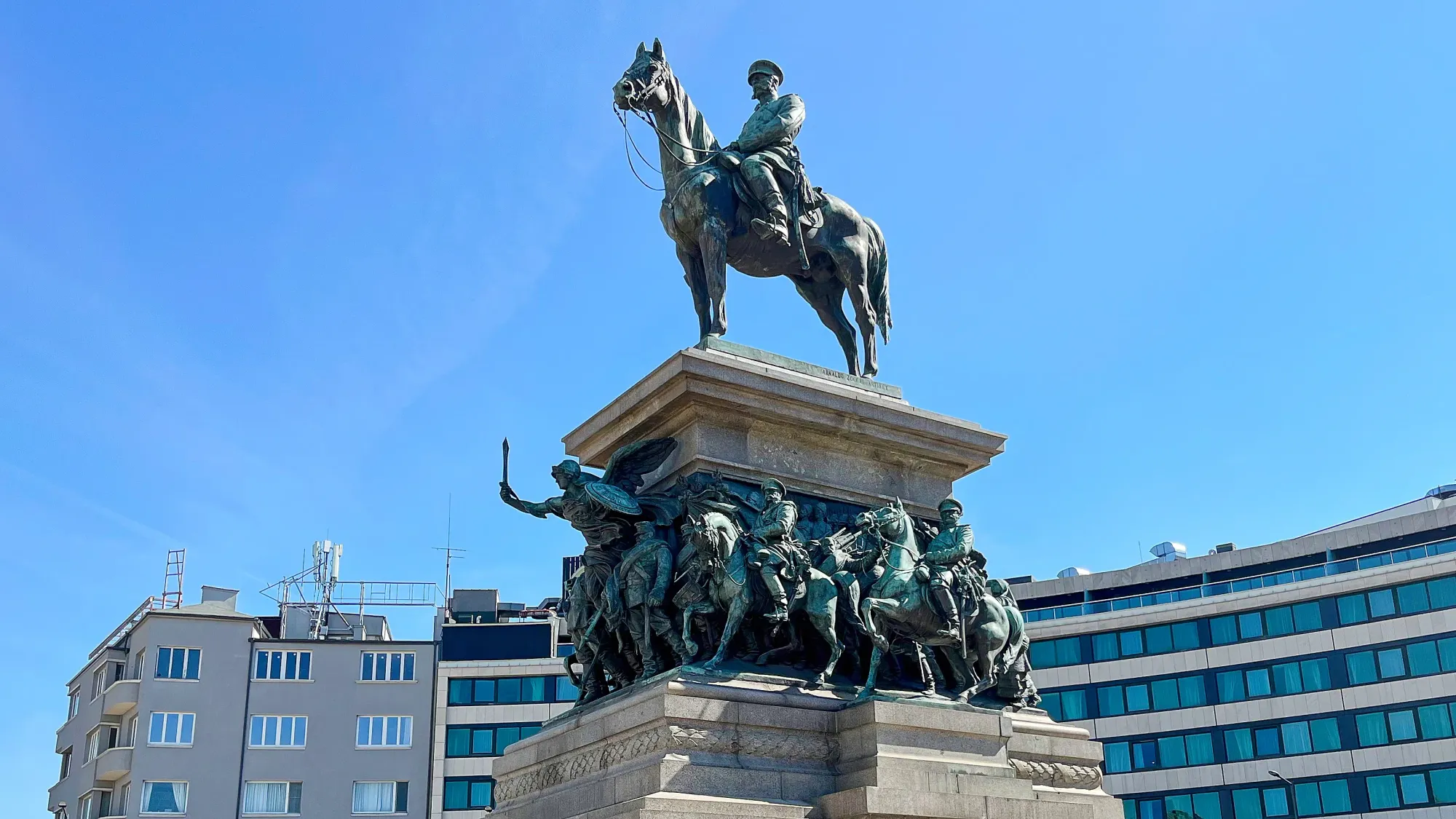 Bronze statue of a man on horseback above a pile of other horse-riders