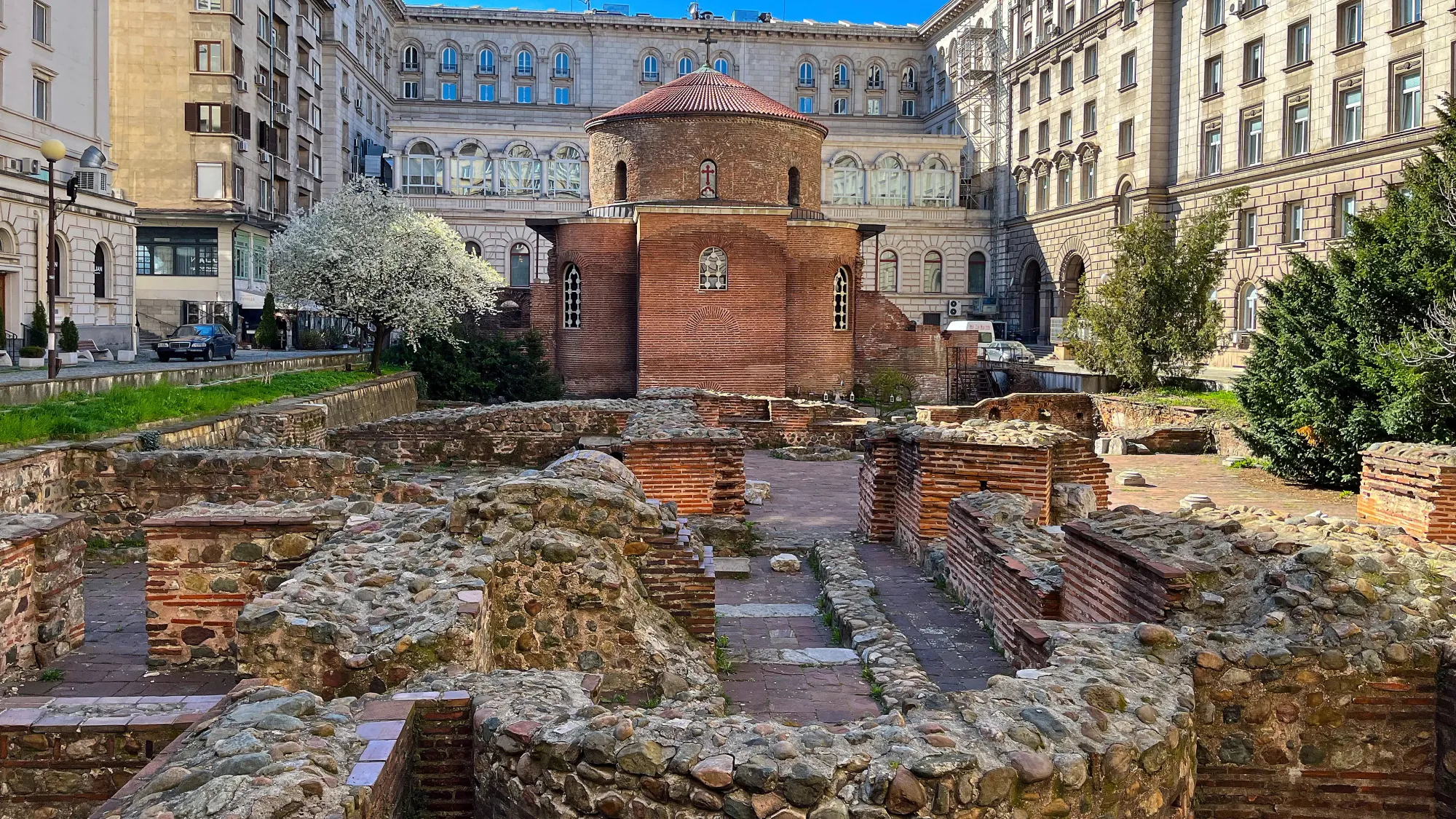 Brick church with stone/brick ruins laying in front of it