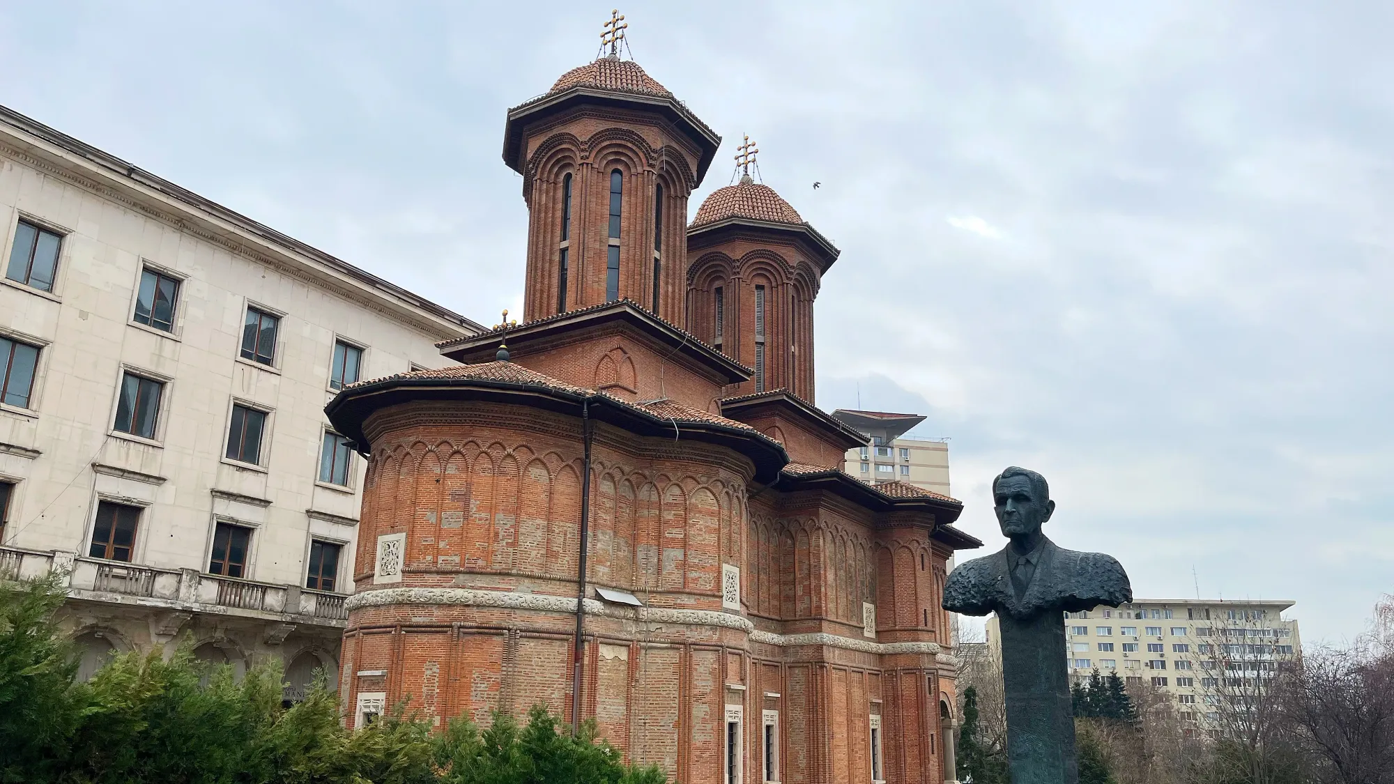 Brick steepled structure with a statue-bust in the foreground