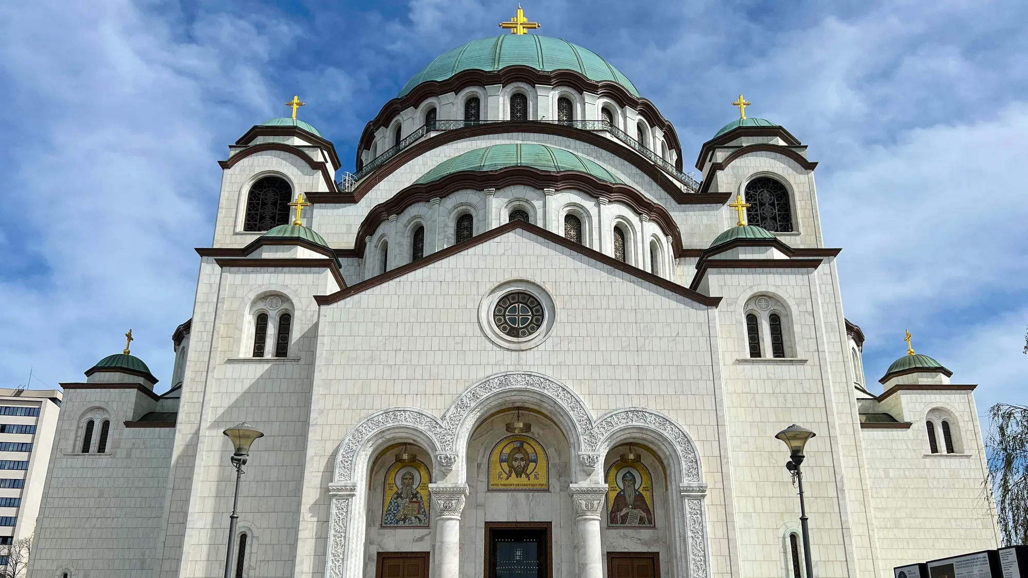 White stone facade with green roof and small golden mosaic details