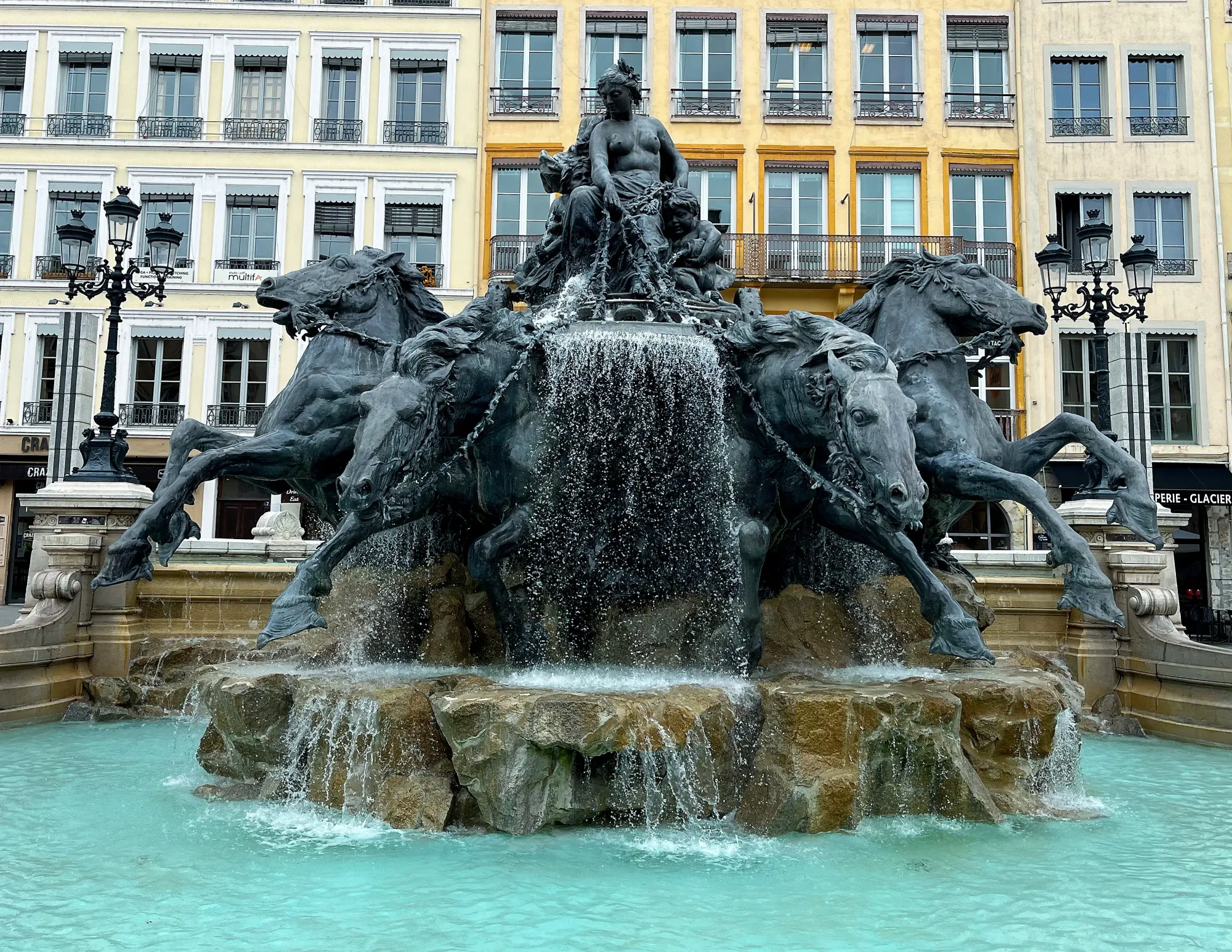 Black fountain of a woman driving a chariot led by four thundering horses