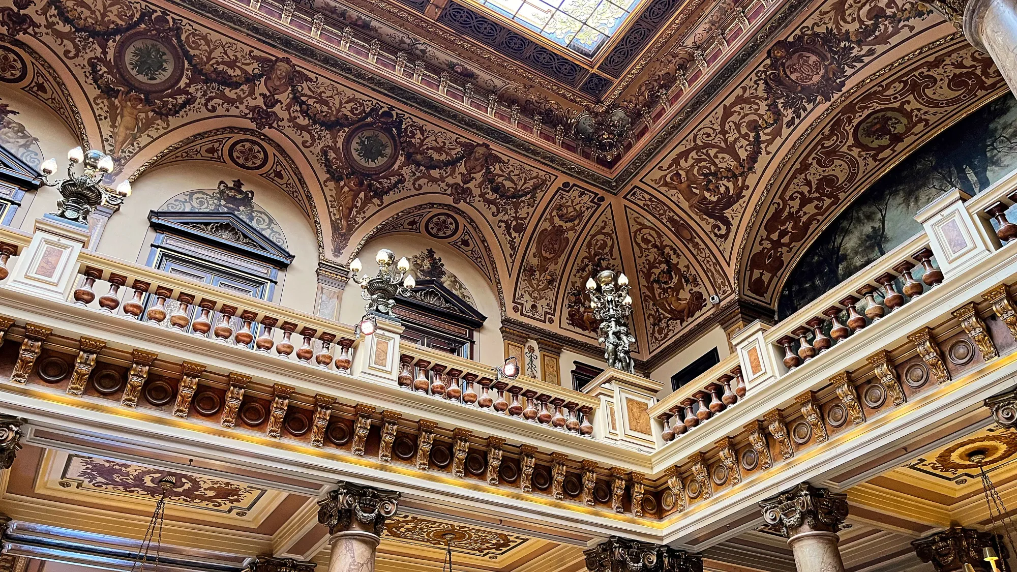 Ornate second story with scrollwork, carved railings, and stained glass