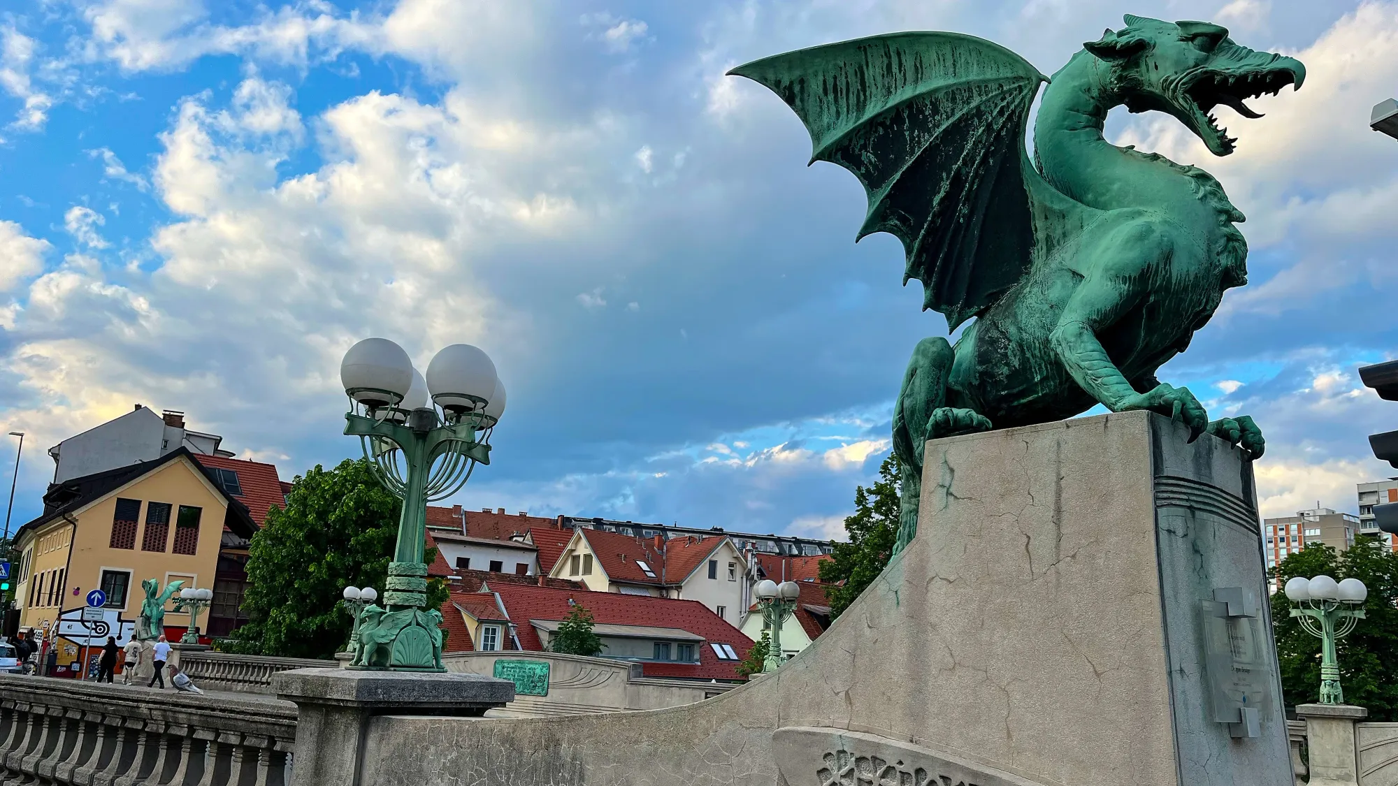 Patinaed dragon sculpture nested atop a stone bridge