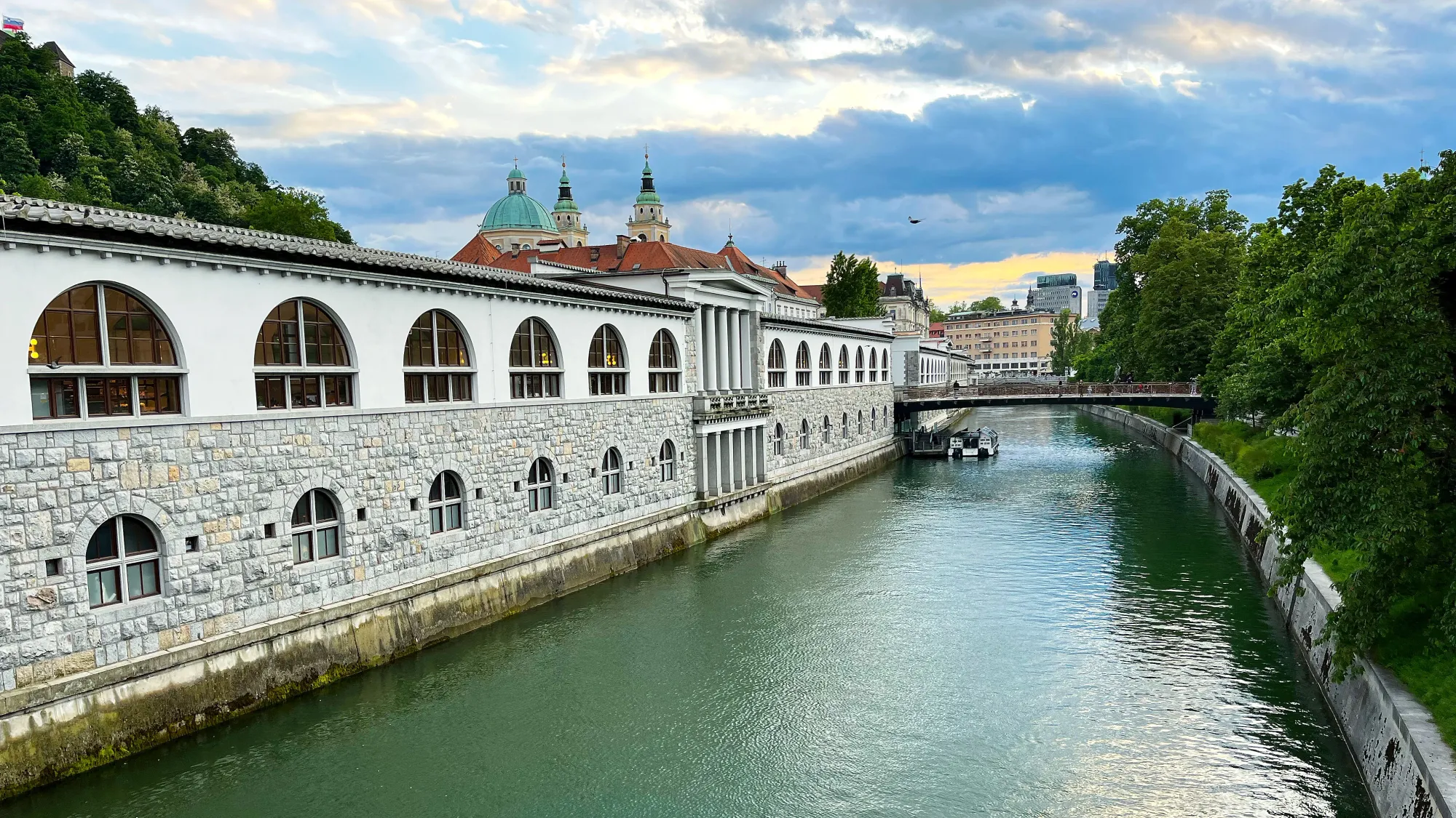 River with a stone building abutting it and bridge crossing over it during dusk