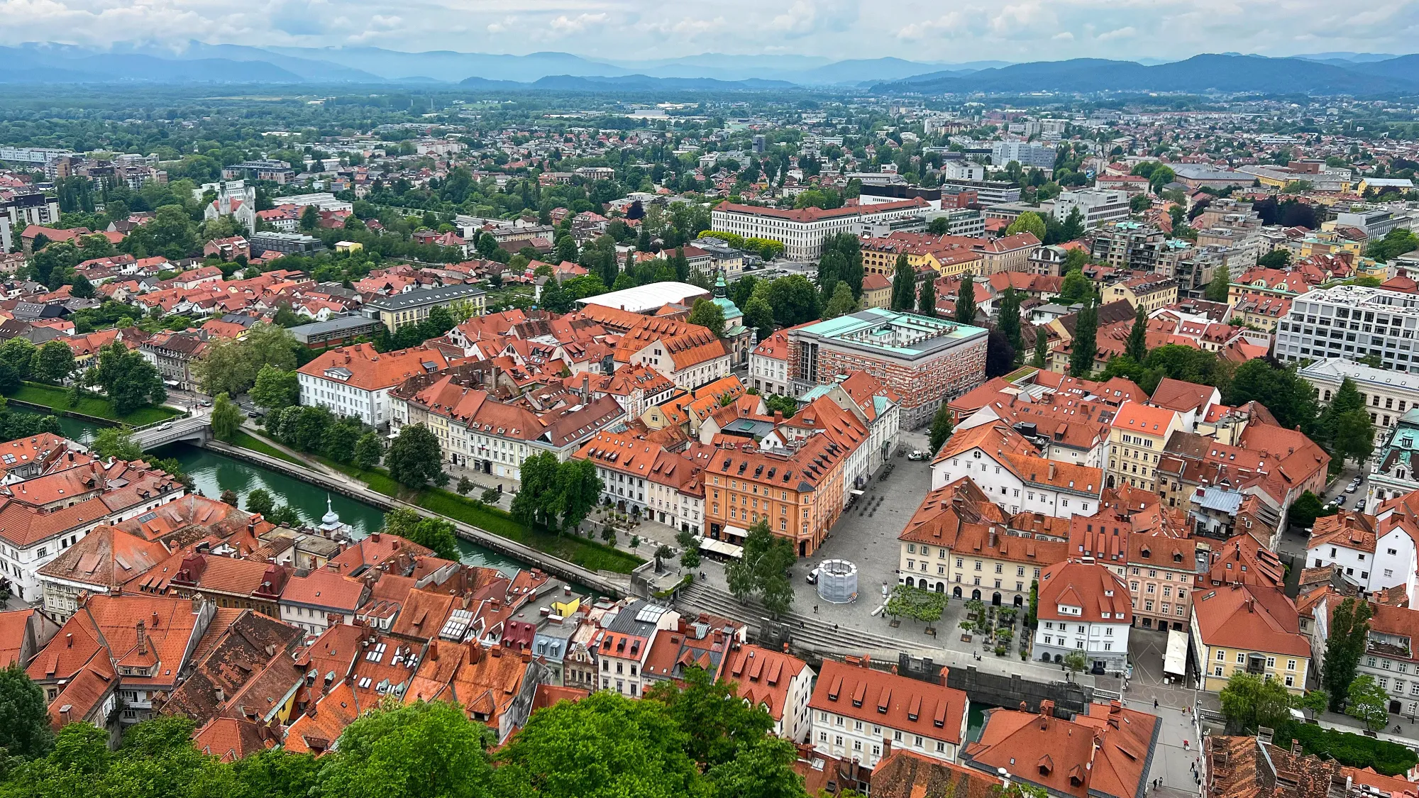 Birds-eye view of the orange roofs of the city interspersed with many lush trees