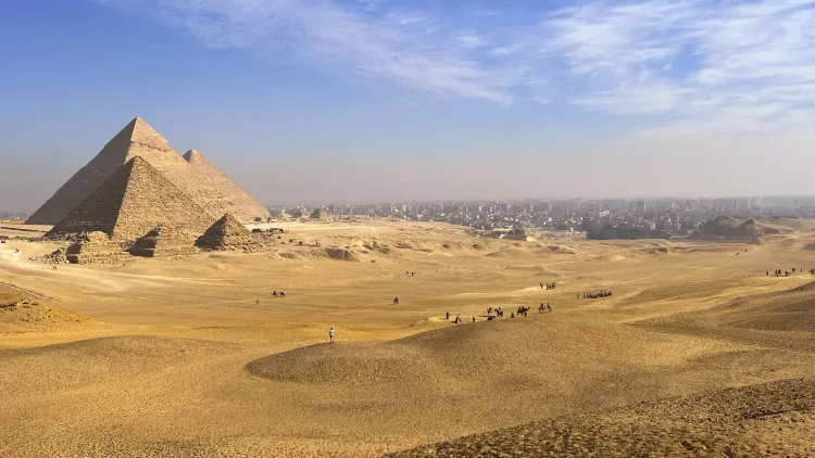 Sandy landscape overlooking the Great Pyramids of Giza with the city in the background