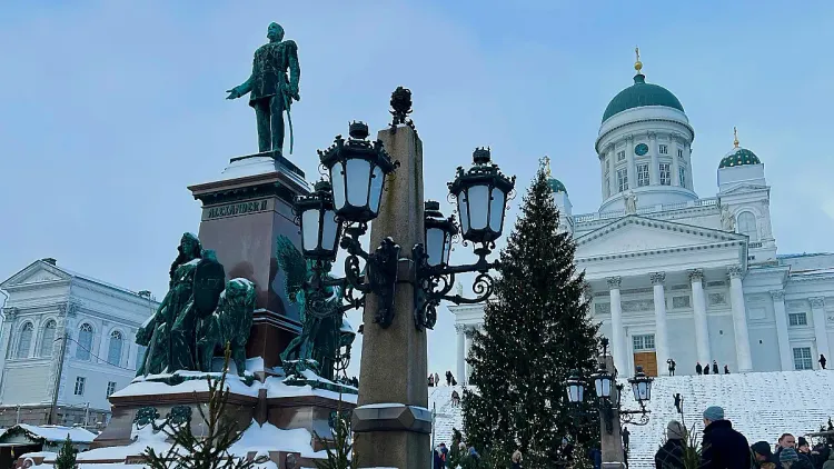Snow covered church in the background, oxidized coper statue and lamp post in the foreground