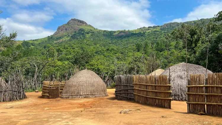 Grass huts and fencing with a mountain in the background