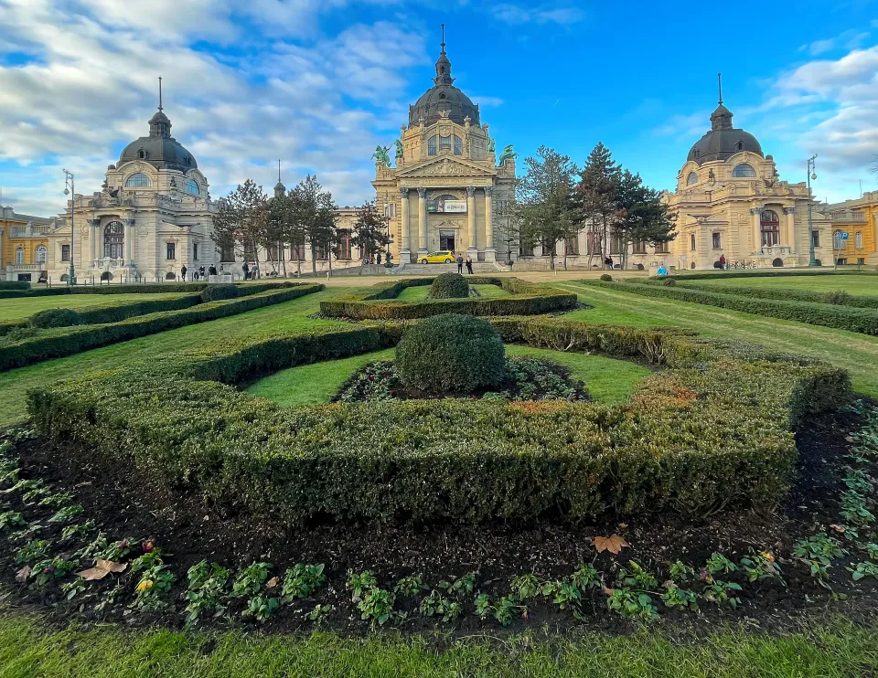 Manicured bushes in front of a sprawling shone facade