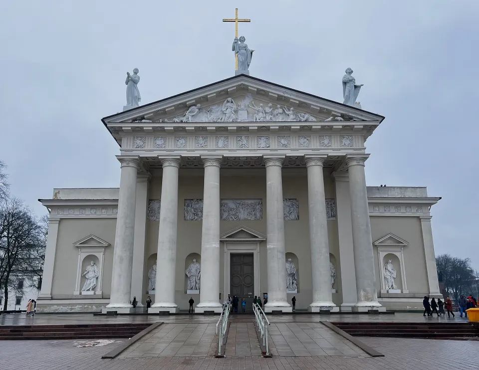 White columned building with statues and a dual ramp in the front