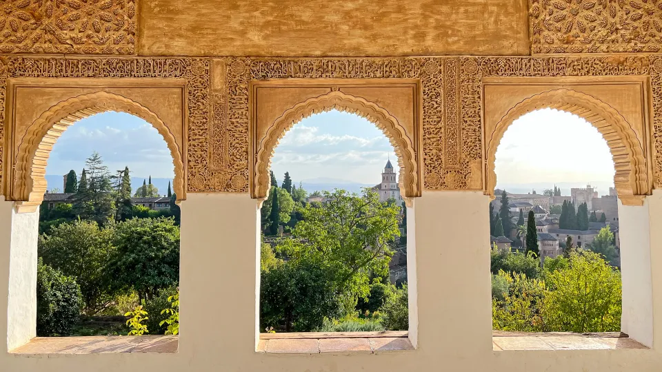 Intricately carved windows overlooking a garden and palace peaks